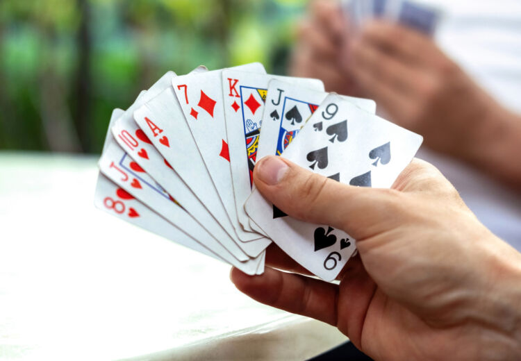 A man playing cards with other people holding a deck